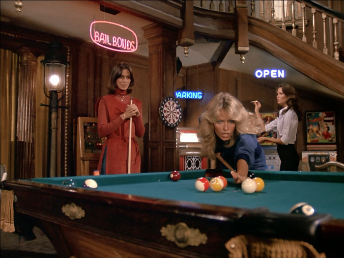 In Charlie's game room, Jill and Sabrina play a game of pool while Kelly plays darts.
