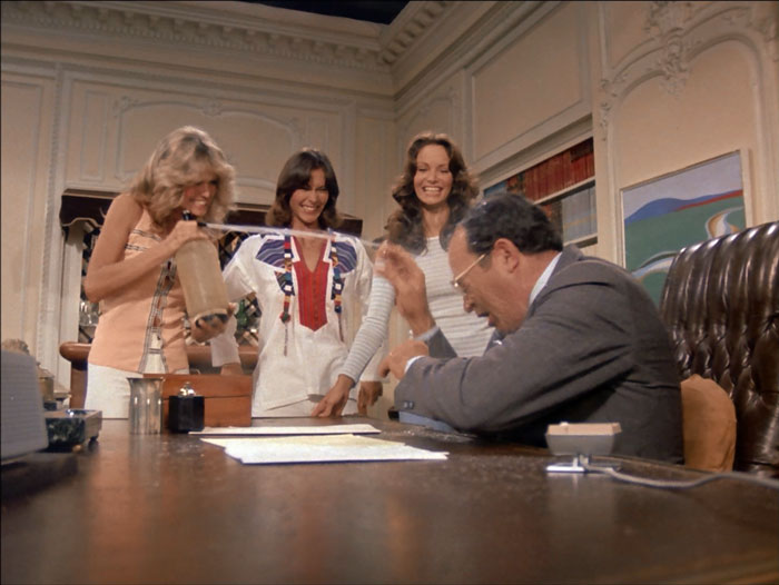 Jill sprays Bosley with a selzer bottle as Sabrina and Kelly look on with laughter.