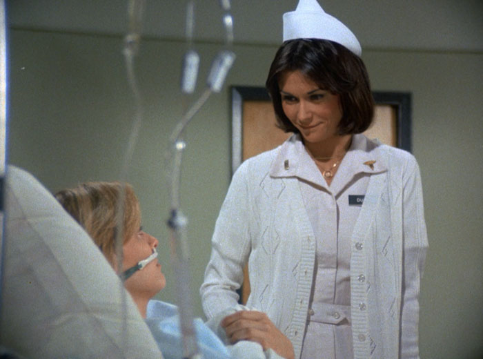 Sabrina (Kate Jackson) in her nurse uniform standing by the bedside of Jenny (Marla Pennington)
